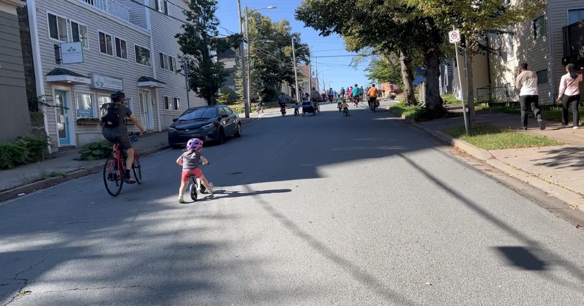 
A small child is on a balance bike on Queen Street in Dartmouth. They are mid stride in the sunshine.

