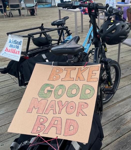 
A sign on the back of a bike reads "bike good mayor bad"
